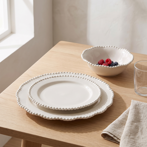 White beaded pearl rim stoneware plates and dessert bowl set on a pale oak dining table