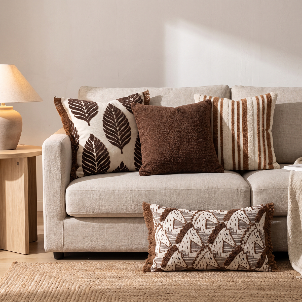 Brown leaf, striped and chenille cushion covers on a linen sofa