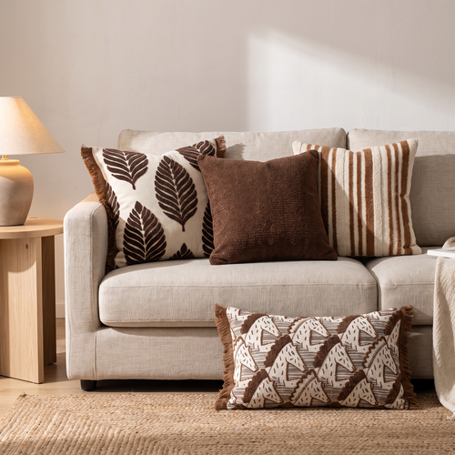 Brown leaf, striped and chenille cushion covers on a linen sofa