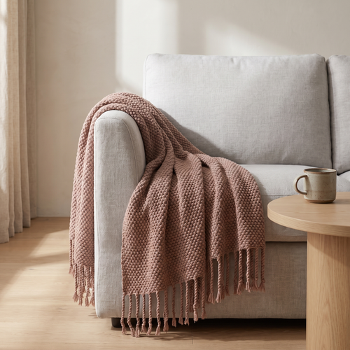 Chunky knit throw with tassels draped over a sofa