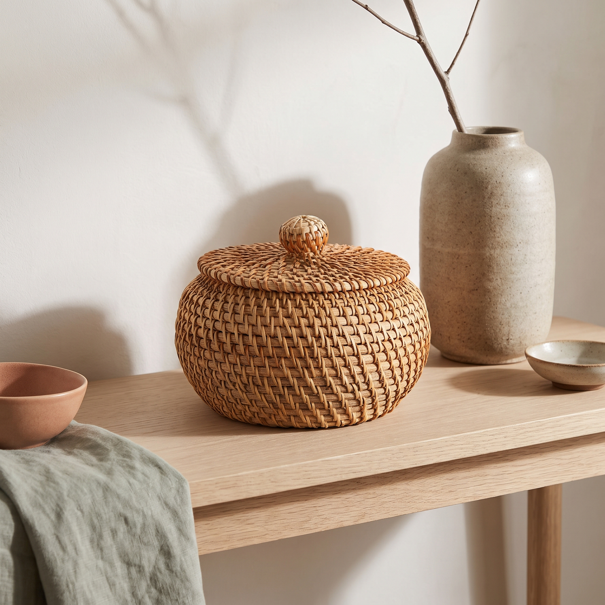 Small round rattan basket with lid on an entryway console