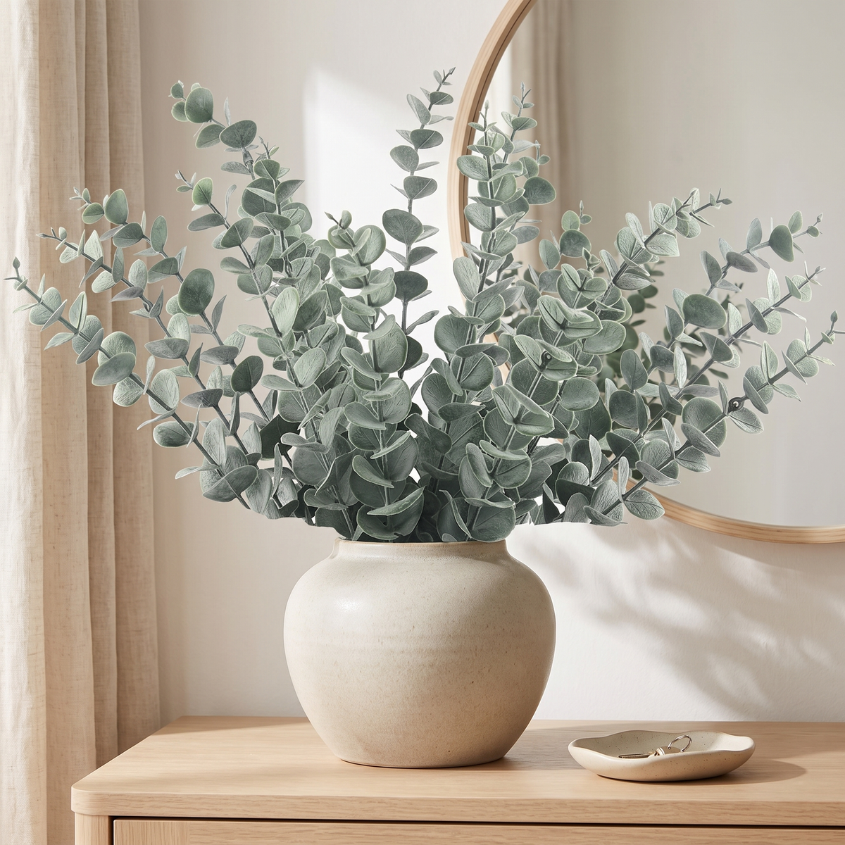 Artificial eucalyptus stems in a stoneware vase on an entryway console
