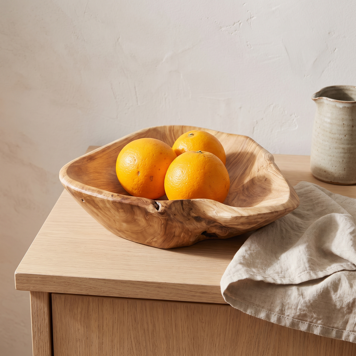 Hand-carved root wood bowl with oranges on a kitchen island